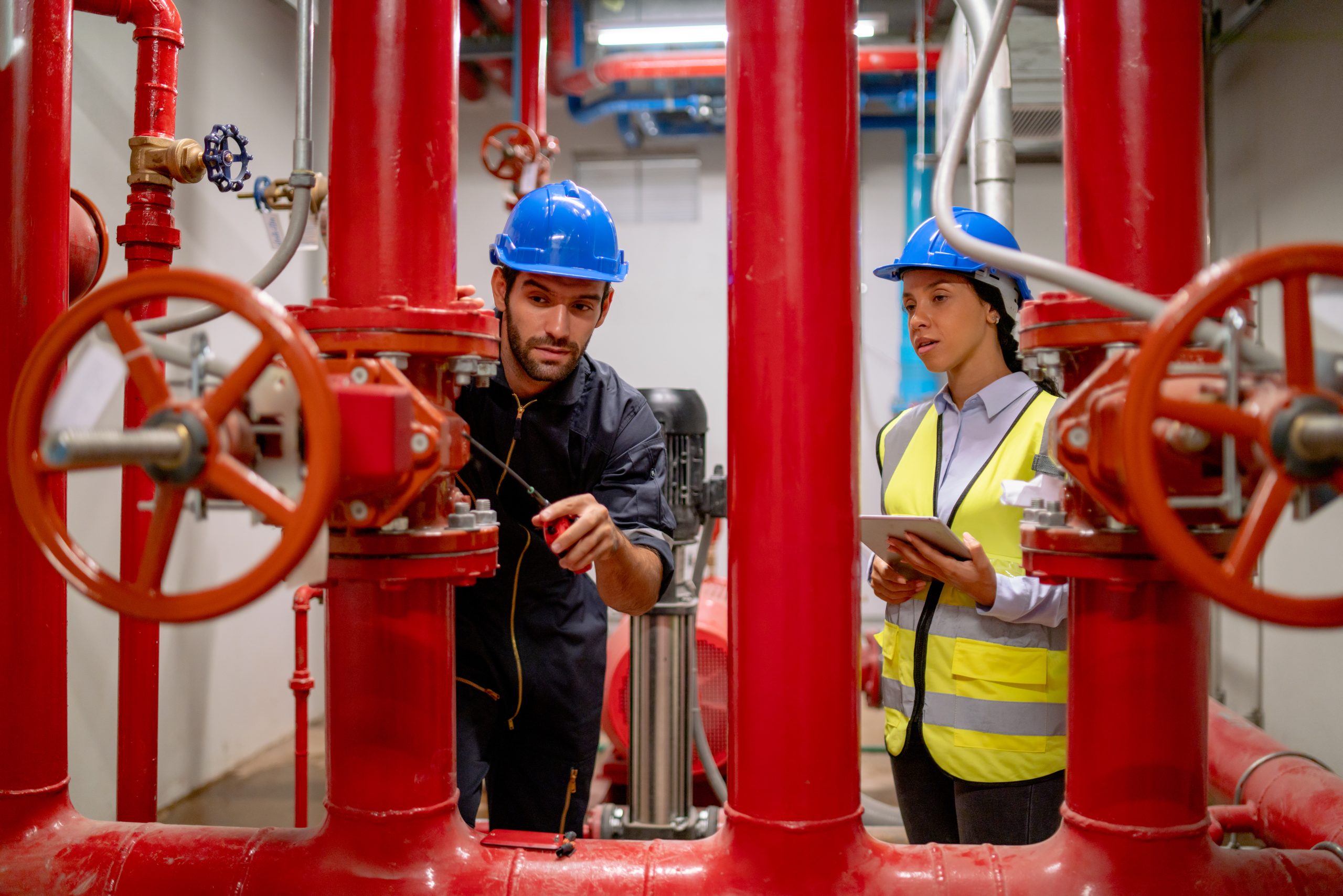 Deux ingénieurs ou techniciens discutent du système de canalisations rouges sur le chantier de construction pour entretenir et résoudre le problème ensemble.